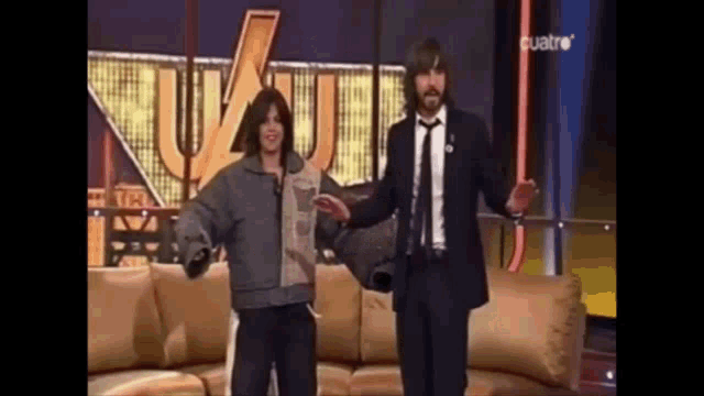 a man in a suit and tie is dancing with a woman on a couch .