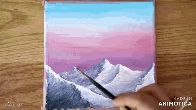 a person is painting a mountain range with a brush on a canvas