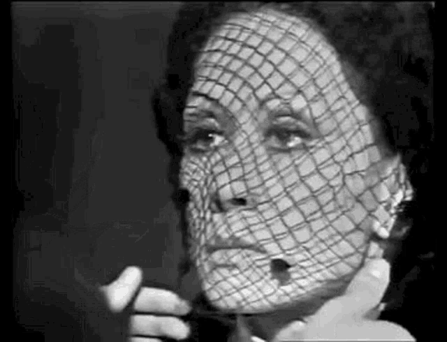 a black and white photo of a woman 's face with a veil on it .