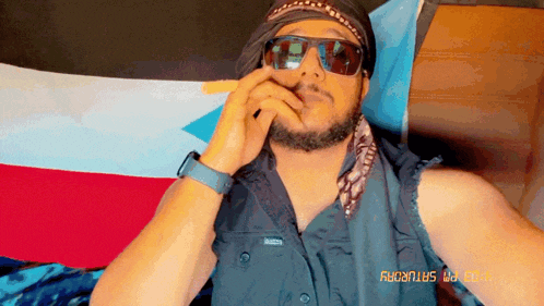 a man wearing sunglasses and a bandana has the date saturday on his shirt