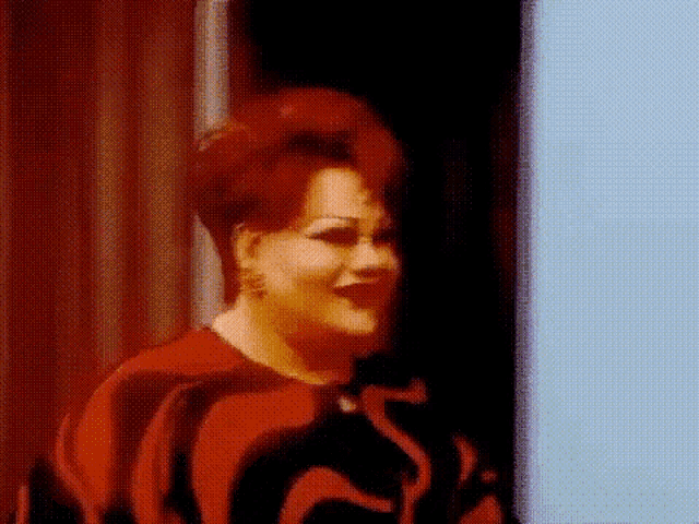 a woman in a red and black dress is standing in a doorway .