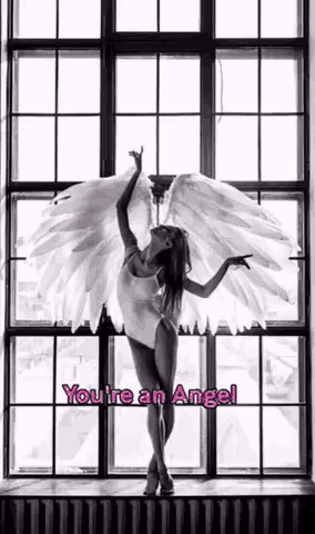 a woman with angel wings is standing in front of a window in a black and white photo .
