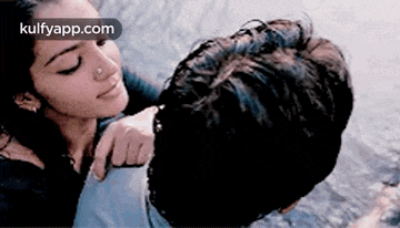 a man and a woman are hugging and kissing in the water .