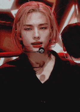 a man with red hair is wearing a black shirt and a microphone around his neck