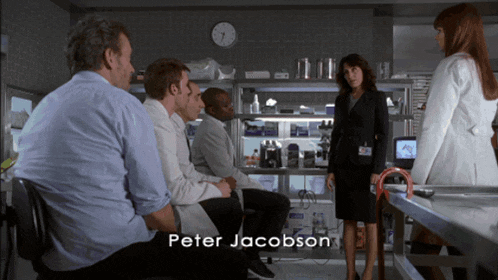 a group of people sitting around a table with the name peter jacobson on the bottom right