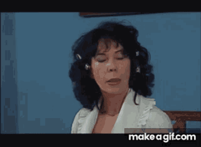 a woman with black hair is sitting in a chair with her eyes closed