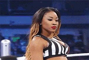 a woman wearing a black and white striped top is standing in a boxing ring .
