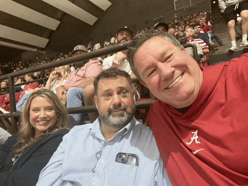 a man wearing a red shirt with the letter a on it smiles for the camera