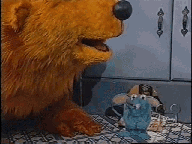 a stuffed bear is sitting next to a stuffed mouse on a tiled floor .
