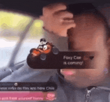 a person is driving a car and holding a toy car in their hand .