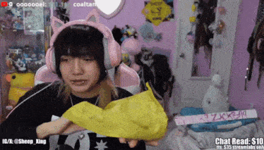 a girl wearing pink headphones is holding a yellow object in front of her face
