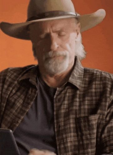 an older man wearing a cowboy hat and plaid shirt