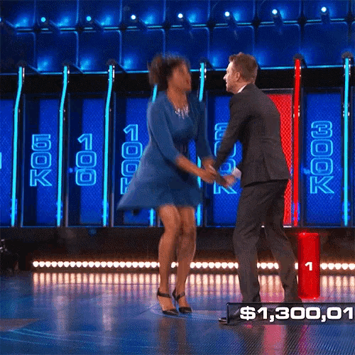 a woman in a blue dress is dancing with a man in a suit in front of a sign that says $ 1,380.00