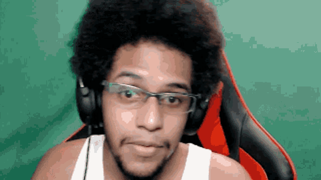 a man wearing headphones and glasses is sitting in a red chair