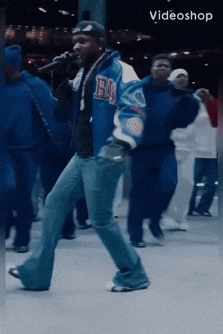 a man wearing a blue jacket with the letter b on it is singing into a microphone