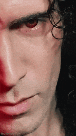 a close up of a man 's face with curly hair and red eyes