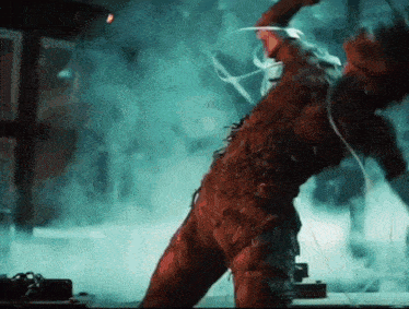 a person in a costume is dancing in a dark room with smoke coming out of the ceiling .
