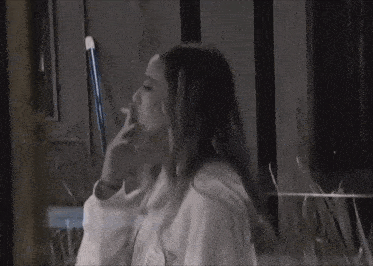 a woman is smoking a cigarette while sitting on a bench .