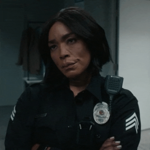 a woman in a police uniform has her arms crossed and a badge on her chest