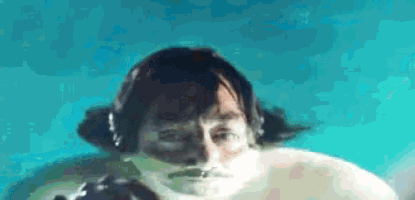 a man with a mustache is swimming underwater in a swimming pool .