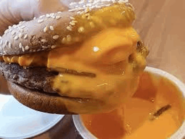 a close up of a hamburger with cheese and sauce on a table .