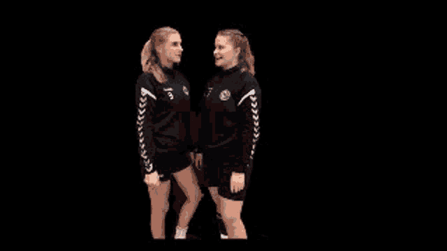 two women are standing next to each other on a black background and smiling