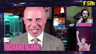 a bald man in a suit and tie is smiling in front of a microphone .