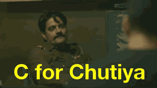 a man in a military uniform sits at a desk with the words " c for chutiya " on the bottom