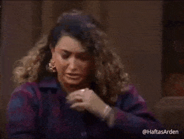 a woman in a plaid jacket is holding a napkin to her face .