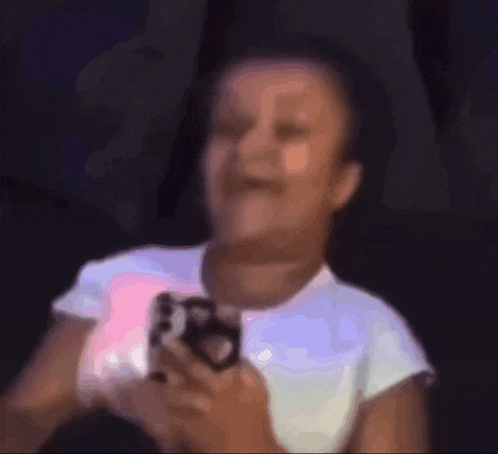 a blurry picture of a girl holding a camera and making a funny face .