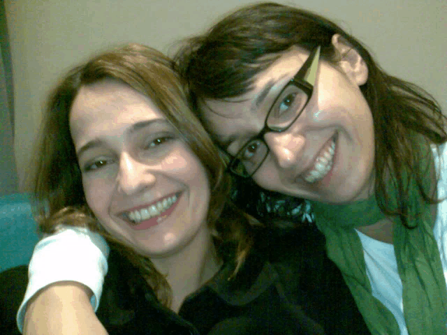 two women wearing glasses and a green scarf are smiling for the camera