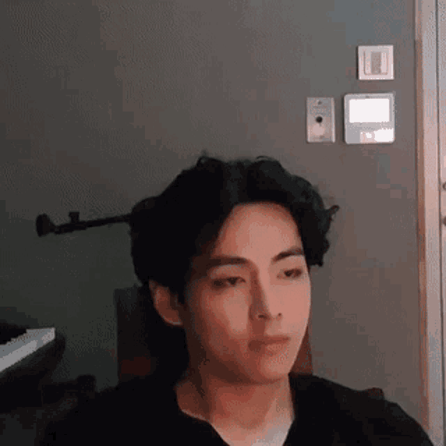 a man with curly hair is sitting in a chair in front of a door .