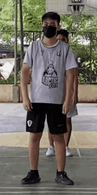 a man wearing a mask is standing on a basketball court wearing a arctic fox jersey .