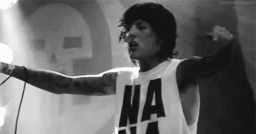 a black and white photo of a man singing into a microphone while wearing a shirt that says `` na '' .