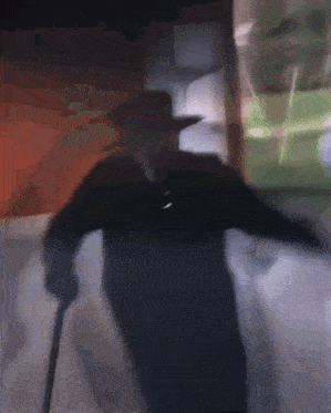 a man with a cane and a hat is standing in the dark