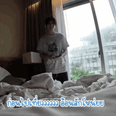 a man playing a video game in a bedroom with foreign writing on the bottom