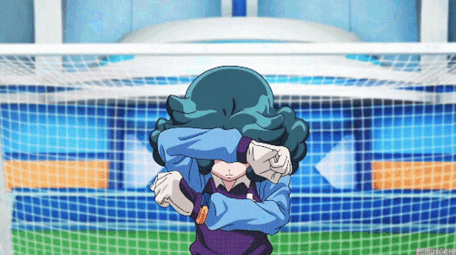 a person covering their face with their hands in front of a soccer goal