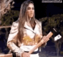 a woman in a leather jacket is holding an axe .