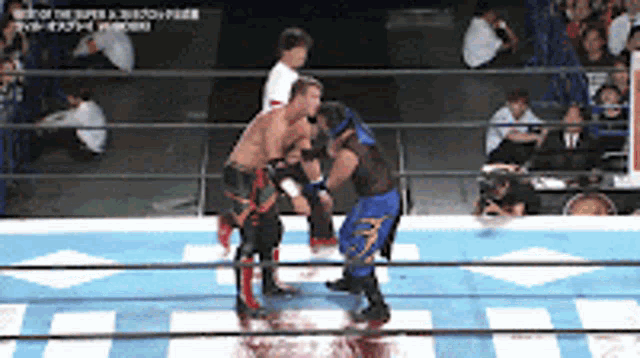 two wrestlers are fighting in a ring with a referee in the background