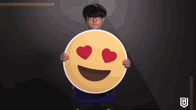 a person holding a large smiley face with hearts in their eyes