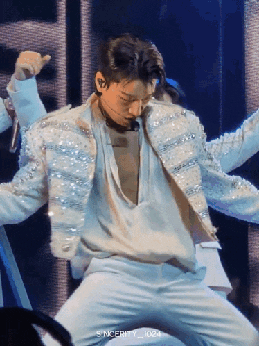 a man in a white jacket and white pants is dancing on a stage with sincerity_1024 written below him
