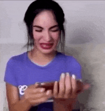 a woman is crying while holding a cell phone .