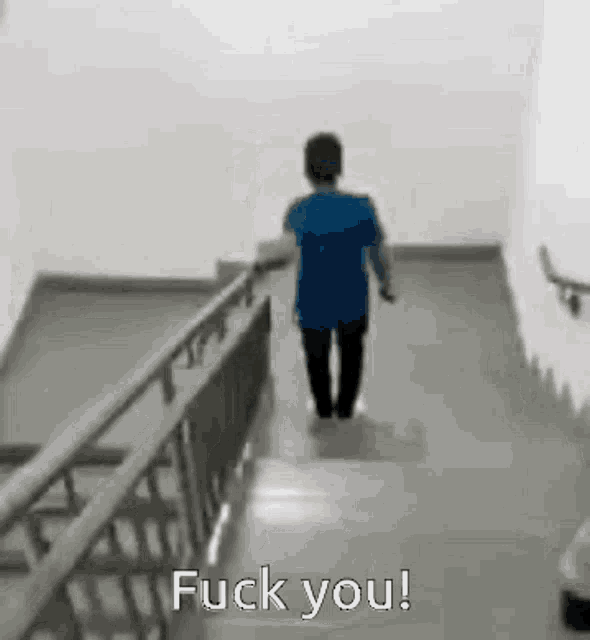 a man is walking down a set of stairs with the words `` fuck you '' .