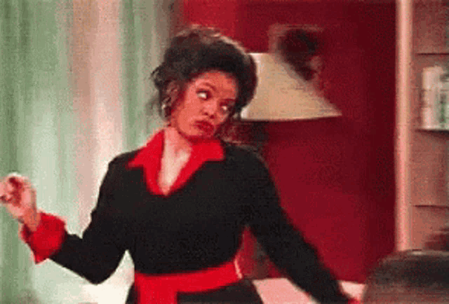 a woman in a black sweater and red collar is dancing in a room .