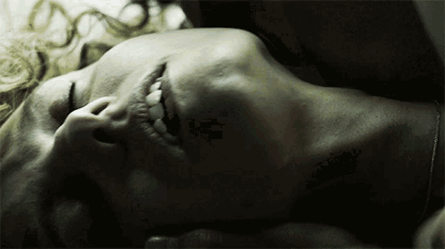 a close up of a woman laying down with her eyes closed and her mouth open