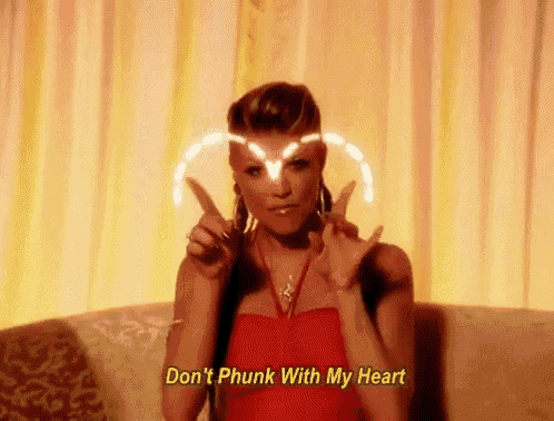 a woman in a red dress is sitting on a couch and making a peace sign with her fingers .
