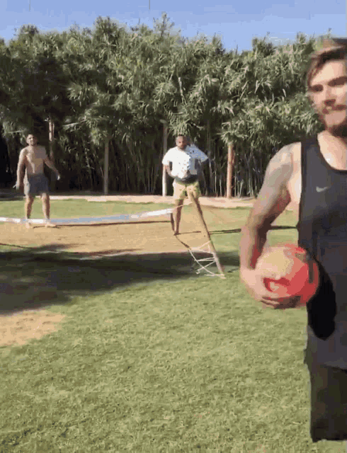 a man in a black nike tank top is holding a red ball in his hand