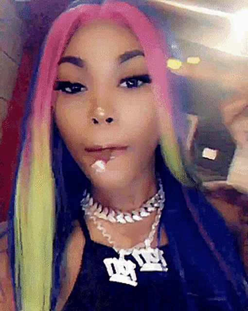a woman with rainbow hair is wearing a necklace with the letter d on it ..