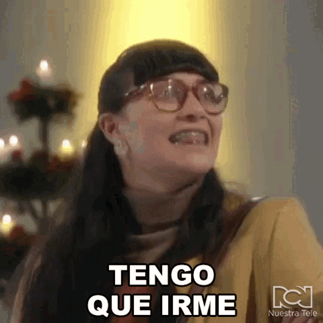 a woman wearing glasses is making a funny face and saying tengo que irme .