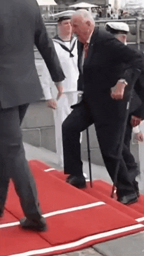 a man with a cane is walking on a red carpet